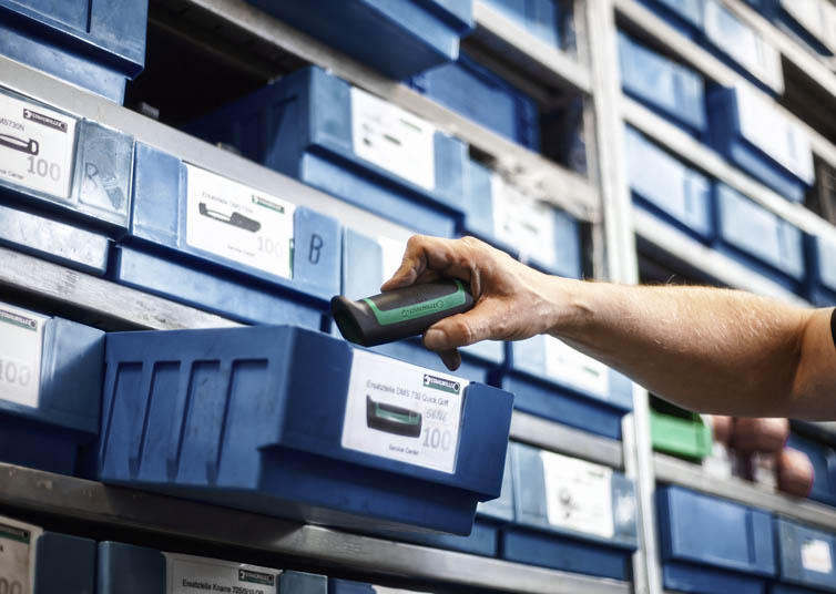 The employee picks up a spare part from a blue box at the STAHLWILLE spare parts warehouse