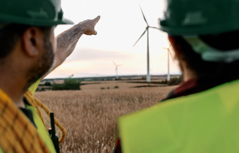 Técnicos de servicio de STAHLWILLE apuntando con el dedo hacia los aerogeneradores